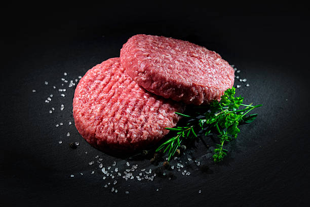 istock Raw beef hamburger patties with spices 589125396