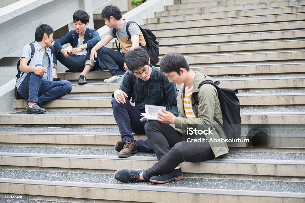 Five Japanese Students Having Fun on Staircase, Campus, Kyoto, Japan Two students reading Manga book, three male Japanese students discussing on the staircase, university campus, Kyoto, Japan, Asia. Copy space. Selective focus. Nikon D800, full frame, XXXL. iStockalypse Kyoto 2016. Manga Style Stock Photo