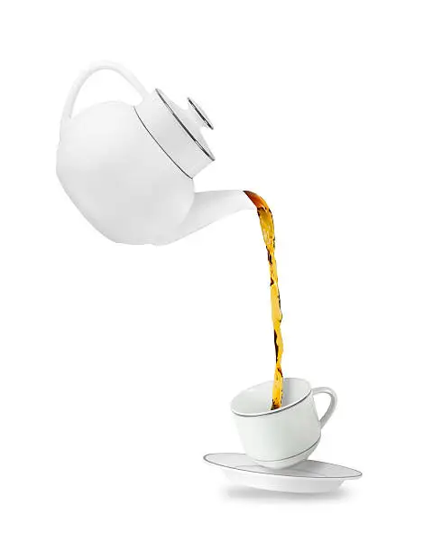 Pouring tea in tea cup. Teapot and cup isolated on white background