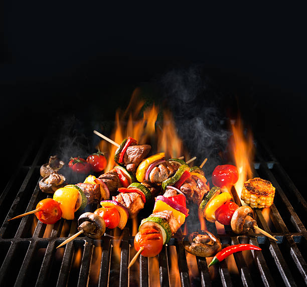 brochettes de viande avec des légumes sur un gril enflammé - barbecue grill broiling barbecue vegetable photos et images de collection