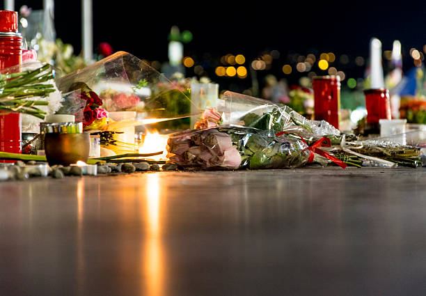 Nice, France Terrorist Attack Memorial Detail Nice, France - August 7, 2016: Candles, flowers and pebbles left at the 'Promenade des Anglais' area in Nice a few weeks after the terrorist attached. Showing the aftermath of the Nice terrorist attack on 14 July 2016. A truck was deliberately driven into crowds on the Promenade des Anglais resulting in the death of 85 people and injuring 307. Logos on candles. islamic state stock pictures, royalty-free photos & images