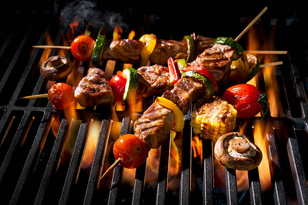 kebabs de carne com legumes na grelha flamejante - barbecue grill broiling barbecue vegetable - fotografias e filmes do acervo