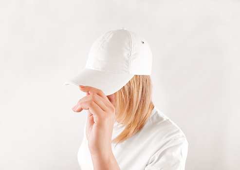 Blank white baseball cap mockup template, wear on women head, isolated, side view. Woman in clear hat and t shirt uniform mock up holding visor of caps. Cotton basebal cap design on delivery guy.
