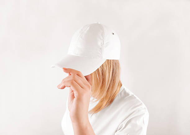 Blank white baseball cap mockup template, wear on women head, Blank white baseball cap mockup template, wear on women head, isolated, side view. Woman in clear hat and t shirt uniform mock up holding visor of caps. Cotton basebal cap design on delivery guy. sideways baseball hat stock pictures, royalty-free photos & images