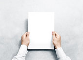 Hand holding white journal with blank cover mockup.