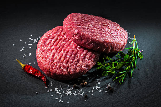istock Raw beef hamburger patties with spices 589130756