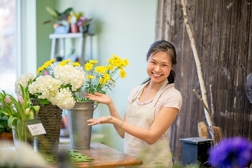 A florist is happily showing her bouquet of flowers. She is smiling and looking at the camera.