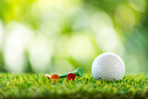 golf ball and wooden tee on grass