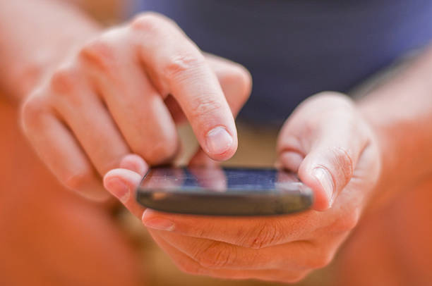 istock Young man sitting in the park and texting a message 589415842
