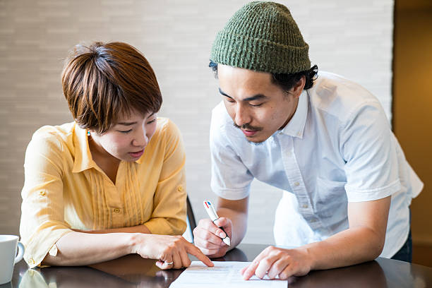 young married couple filling out important paper documents - endorsing business application form filling imagens e fotografias de stock