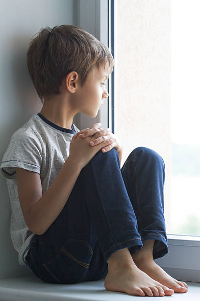 istock Sad lonely child sitting alone on the window at home 589417770