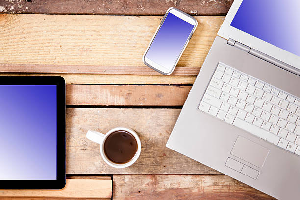 istock Laptop, cell phone, coffee, digital tablet on wooden table. 589418992