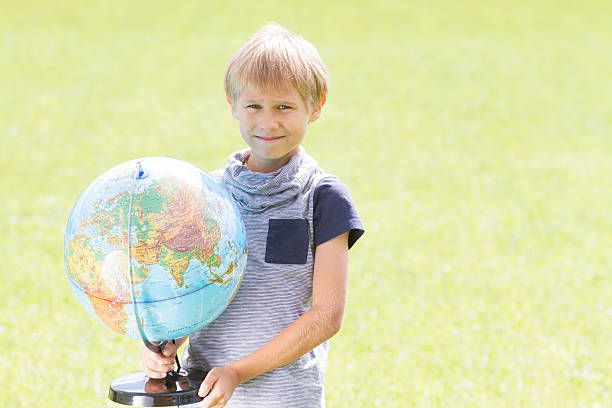 istock Smiling boy with a globe outside. Education Back to school 589419816
