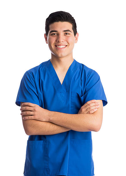 Health care worker standing looking at camera and smiling Front view of a young health care worker standing with arms crossed and smiling at the camera in a vertical waist up shot with white background. medical scrubs stock pictures, royalty-free photos & images