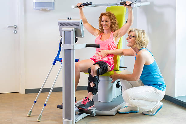 patienten, die hilfe bei der beinrehabilitation erhalten. - physical therapy exercise machine exercising exercise equipment stock-fotos und bilder