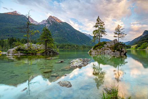 Beautiful scene of trees on a rock island and mountains at sunrise time in summer, Lake Hintersee National park Berchtesgadener Land, Upper Bavaria, Germany, Europe