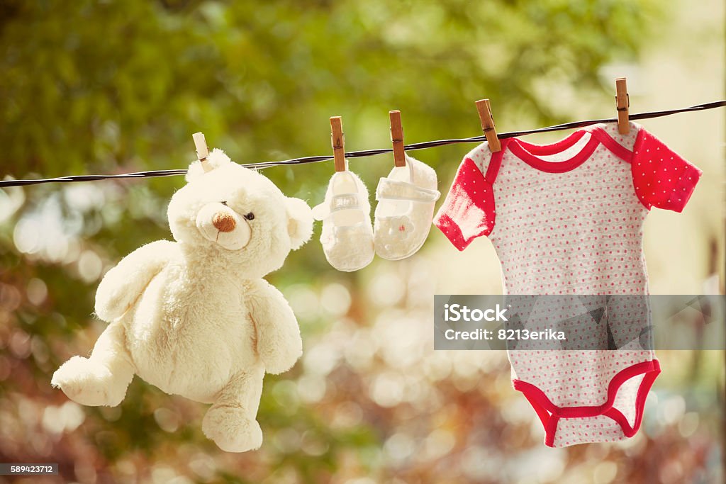 Baby clothes and teddy bear hanging on the clothesline Baby clothes and teddy bear hanging on the clothesline - family concept Child Stock Photo