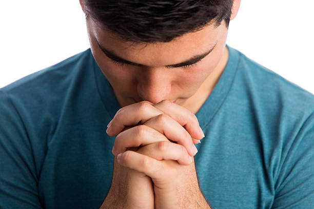 istock Close up of young latin man praying 589423916