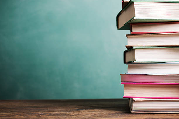 istock Textbooks stacked on school desk with chalkboard background. 589424468