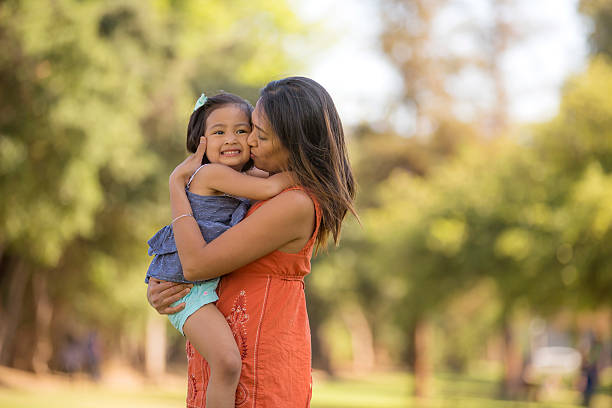 Young ethnic mother embracing her toddler girl outdoors Young ethnic mother embracing her toddler girl outdoors filipino family stock pictures, royalty-free photos & images