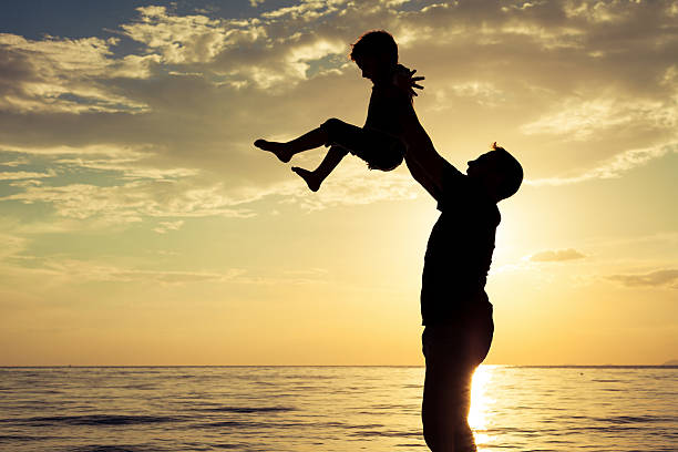 istock Father and son playing on the beach at the sunset 589426552
