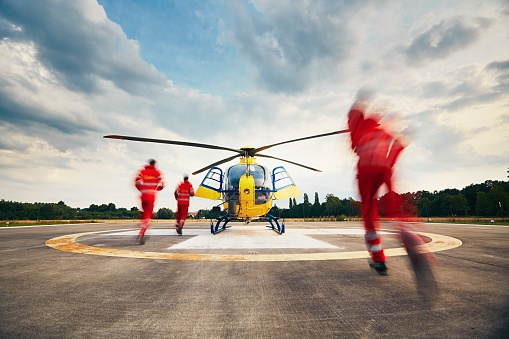 Alarm for the air rescue service. Team of rescuers (paramedic, doctor and pilot) running to the helicopter on the heliport.