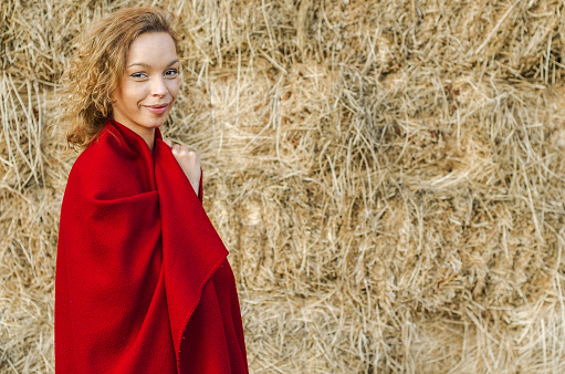 girl or woman in the countryside warpped in a red blanket or layer