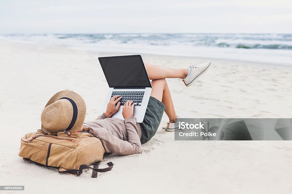 Young woman using laptop on a beach Resting woman using laptop on a beach Beach Stock Photo