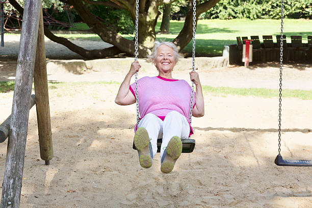 istock cheerful  senior woman on playground using a swing 589430078