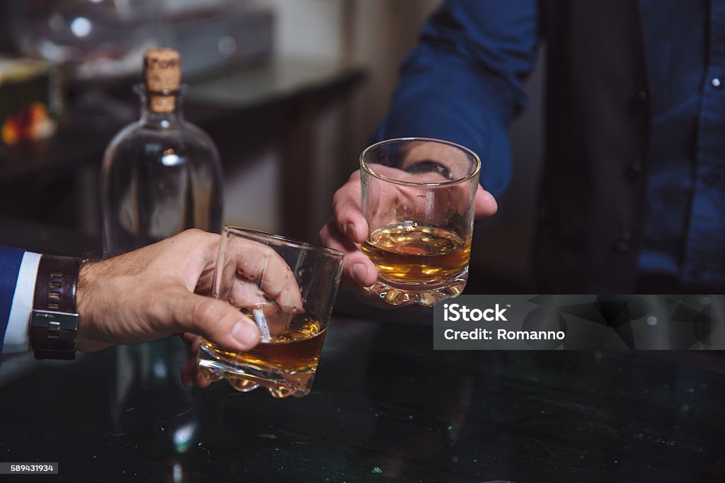 Whiskey glass in a hand of two mans Whiskey glass in a hand of two mans. Alcohol Men Stock Photo