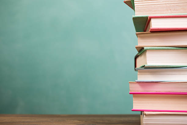 istock Textbooks stacked on school desk with chalkboard background. 589432646