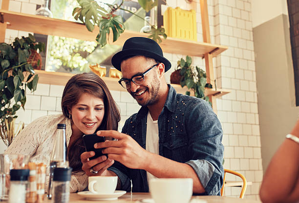 istock Friends looking at mobile phone while sitting in cafe 589434746