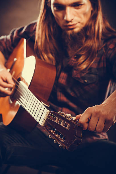 istock Young guitarist is tuning guitar. 589435908
