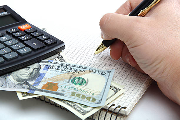 istock Dollars, calculator and hand with pen on the open notebook. 589436300