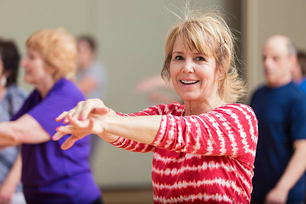 istock Senior woman stretches in exercise class 589436490