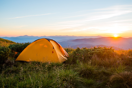 Yellow tent in the mountains, sunrise on the ridge, trekking, travel gear, expedition, tour, conductor