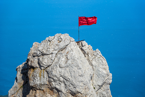 The rock on Mount Ai-Petri with a red flag over Black Sea in Crimea, Russia. Ai-Petri is one of the highest mountains in Crimea and tourist attraction.