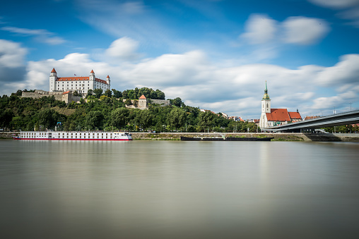 Bratislava, Slovakia - August 15, 2016 - Flowing river Danube with the view of Bratislava castle above and St. Martin's cathedral. This view is from Petrzalka embankment.