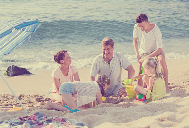 istock family with four kids relaxing on beach 589438572