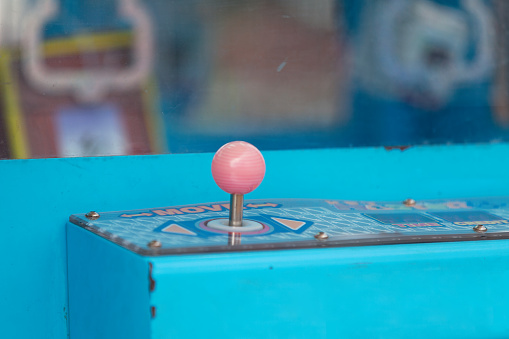 Close up on the joystick of a Claw crane, an arcade game known as a merchandiser.