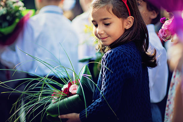 Little girl is bringing flowers on her teacher in the first day at school.