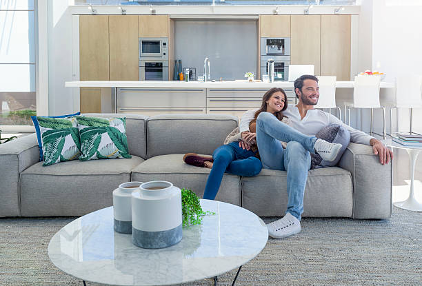 현대적인 오픈 플랜 주택에 앉아있는 커플. - sofa couple relaxation comfortable 뉴스 사진 이미지