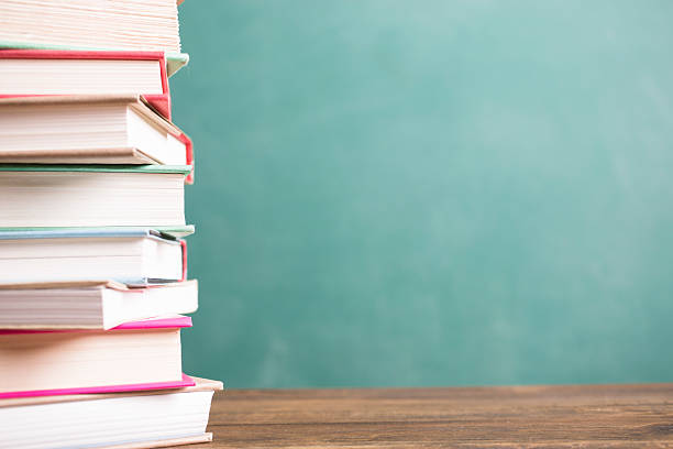 istock Textbooks stacked on school desk with chalkboard background. 589450936