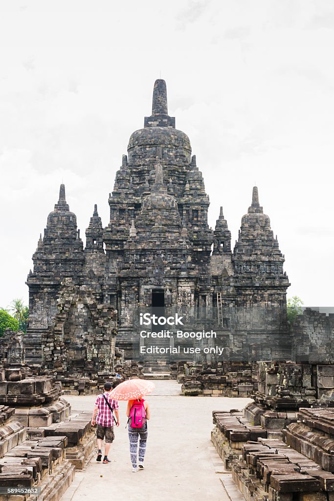 Tourist Visit Ancient Candi Sewu Prambanan Temple in Java Indonesia Prambanan Temple Compounds, Indonesia - April 7, 2015: In Central Java outside of Yogyakarta are the ancient ruins of Candi Sewu built centuries ago. Two tourists walk up toward the Buddhist temple, which is now a UNESCO world heritage site. Prambanan Temple Stock Photo