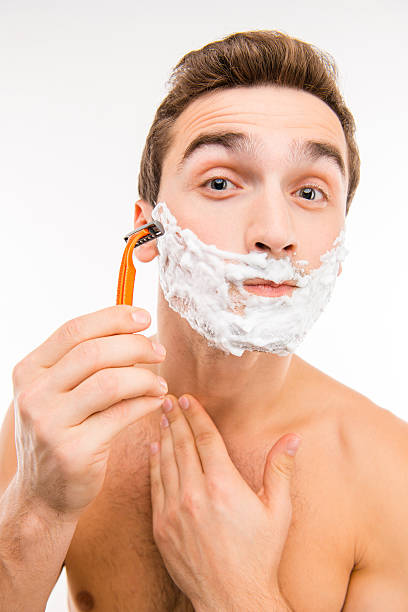 istock Handsomeman with shaving foam on his face and razor 589452768