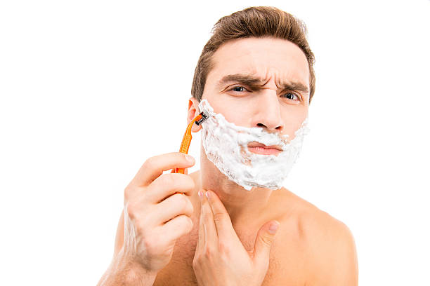 istock Young muscular man shaving over white background 589452774
