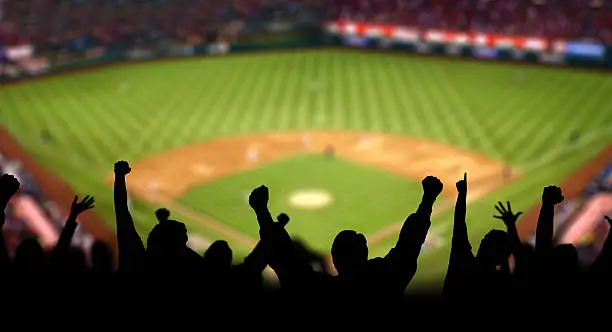 Fans excited lifting hands and pumping fists at a baseball game.