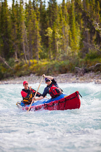 istock Two young men paddle a river in Northern Canada 589454952
