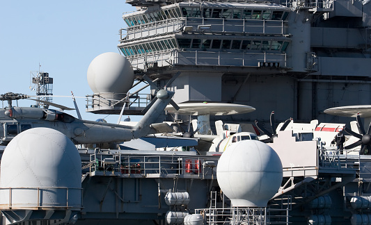 A navy helicopterr on the deck of an aircraft carrier near the bridge