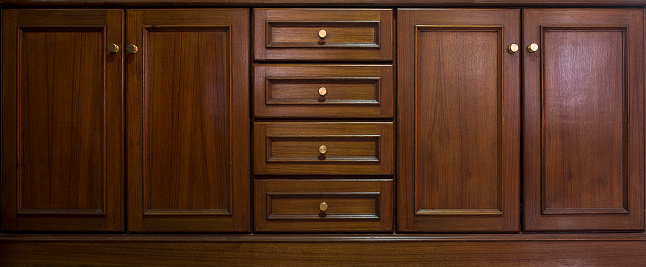 Front kitchen wooden frame cabinet door and drawers made from dark wood, background and texture